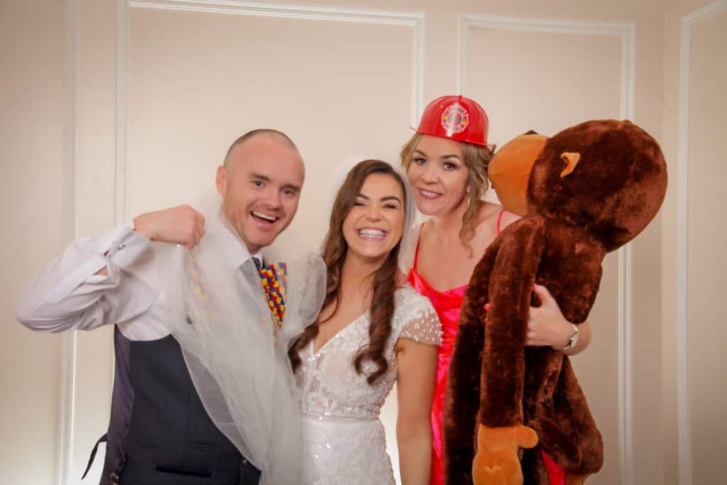 A group of friends celebrating with costumes and a giant teddy bear at Studio Booth.