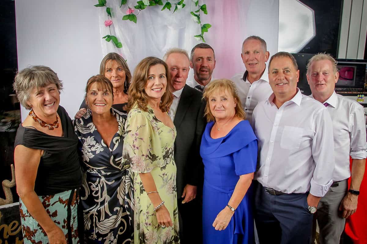 Group of diverse adults enjoying a fun photo booth experience at a social event.