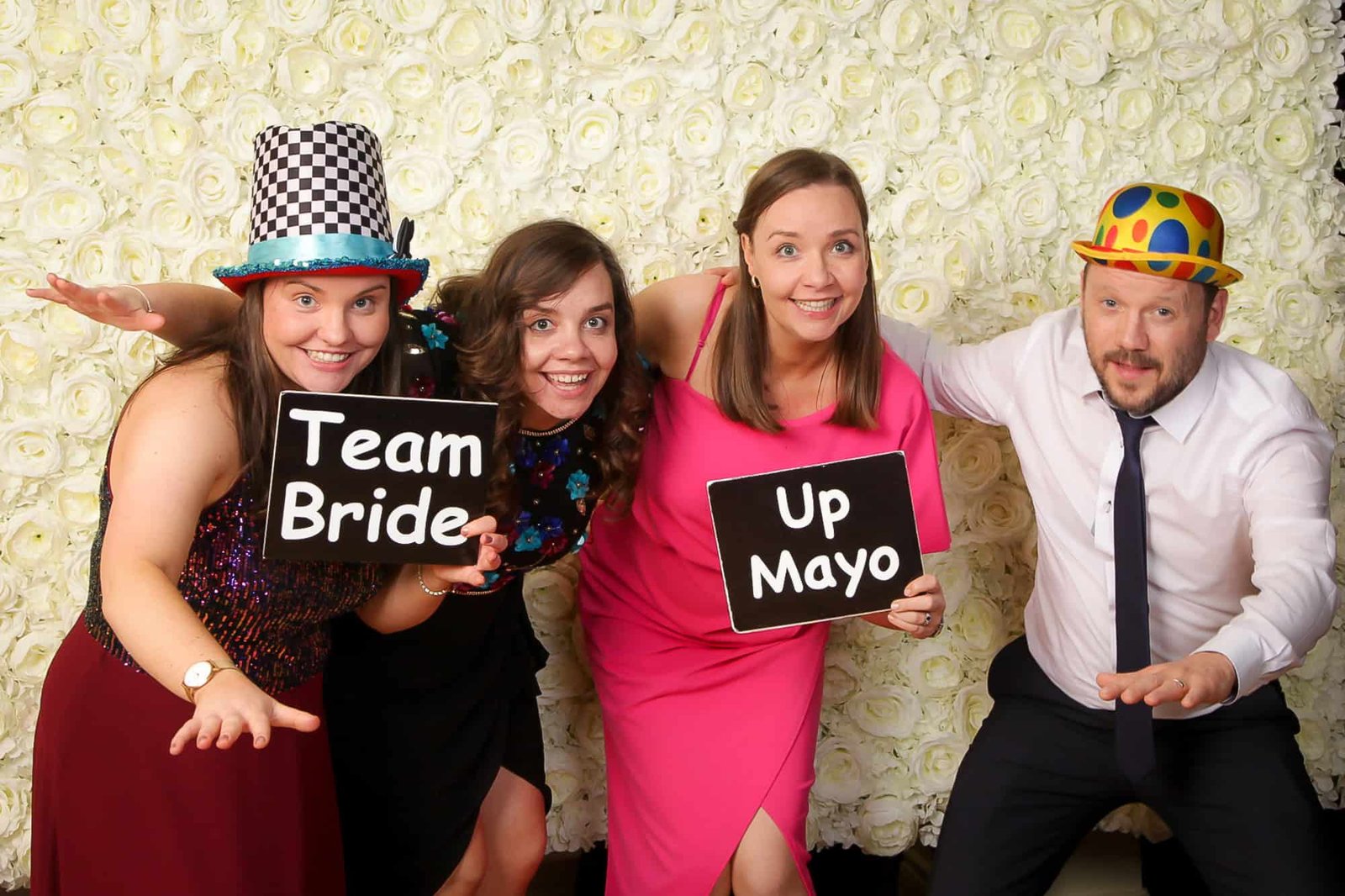 Vibrant wedding photo booth with friends wearing colourful hats and holding signs.